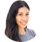 Smiling woman with long dark hair wearing a gray shirt, photographed against a plain white background.
